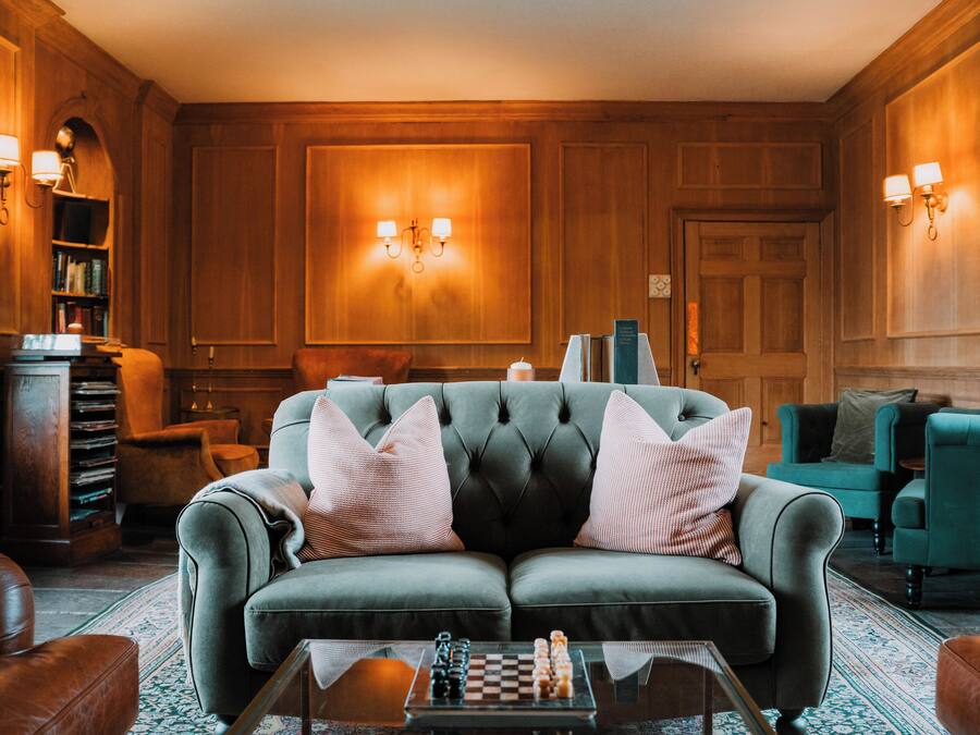 A cozy living room with a tufted sofa, a chessboard, and a bookshelf.