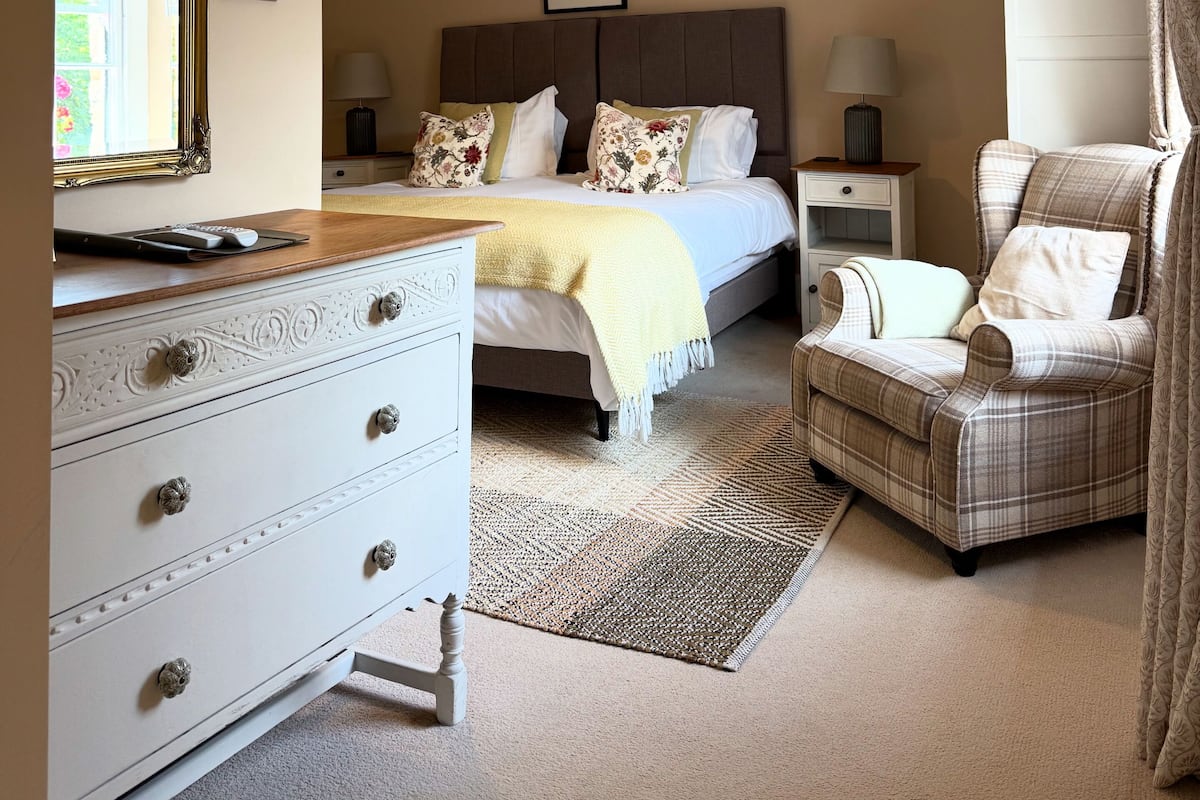 A bedroom with a bed, bedside tables, a dresser, a chair, and a lamp.