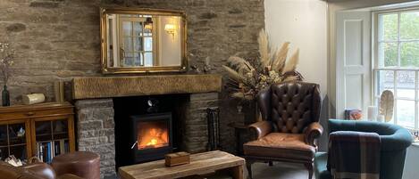 Un salón acogedor con chimenea de piedra, muebles de cuero y un espejo grande.