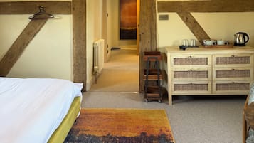 Un dormitorio con cama, cómoda de madera, lámpara colgante y un pasillo que lleva a otra habitación.