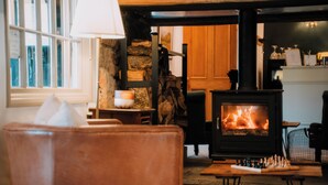 Una habitación acogedora con chimenea, un tablero de ajedrez y una ventana con cortinas.
