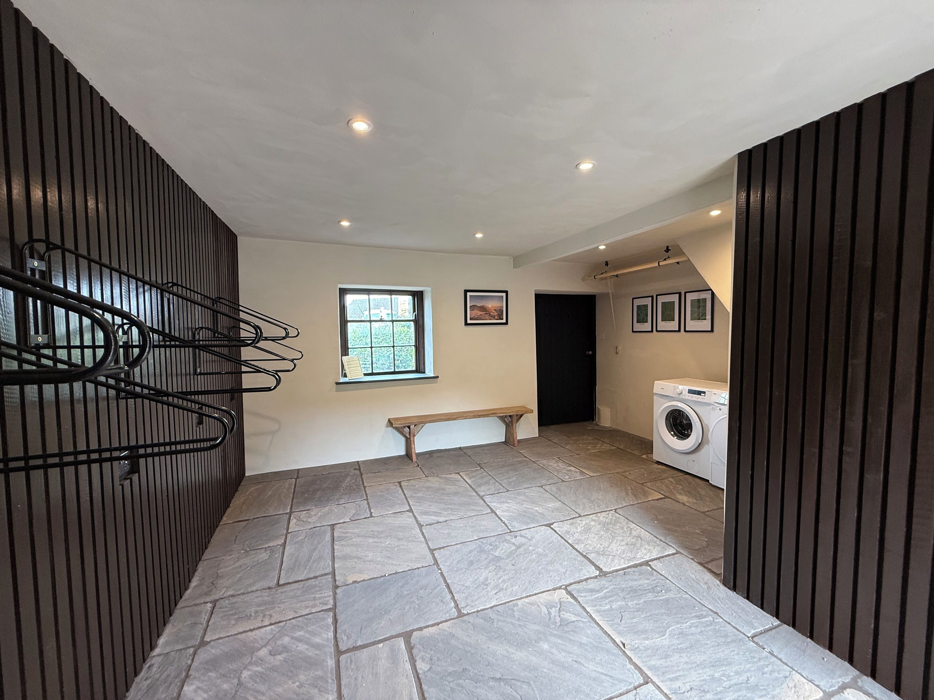 A laundry room with a washing machine, a bench, and a window with a view.