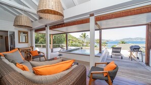 A spacious indoor area with a pool, outdoor seating, and a view of the sea.
