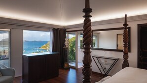 Un dormitorio con cama con dosel, un ventanal con vista al mar y un balcón.