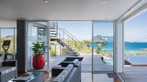 Interior moderno com uma grande porta de vidro deslizante que dá para uma varanda com vista para o mar.
