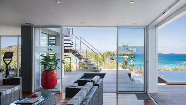 A modern interior with a large sliding glass door leading to a balcony with a view of the sea. - Panama (3/5 Rooms) Luxury villa (Saint Jean)