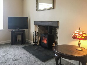 A living room with a fireplace, a television on a stand, and a lamp on a table.