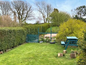A well-maintained garden with a wooden fence, a picnic table, and a tire planter.