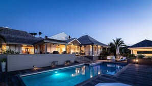 Una casa moderna con piscina, zona de estar exterior cubierta y un patio bien iluminado.