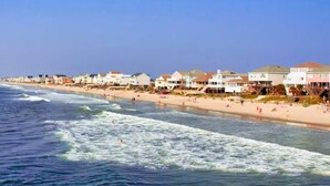 Une plage bordée de maisons le long du rivage, une plage de sable et l’océan.