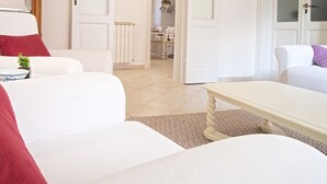 Una sala de estar moderna con un sofá blanco, una manta roja y una mesita de noche con una planta.