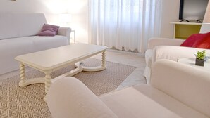 Una sala de estar moderna con un sofá blanco, una mesa de centro blanca y una alfombra estampada.
