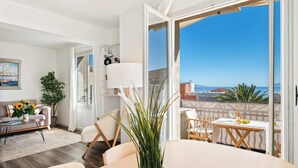 A modern living room with a sofa, a dining table, and a balcony with a view of the sea. - 04. Bright apartment with balcony and sea view, close to the beach (Saint-Jean-Cap-Ferrat)