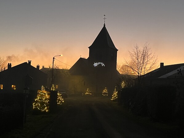 Une  église dotée d’un clocher et d’une lanterne en forme d’étoile au sommet, entourée de maisons et d’arbres.