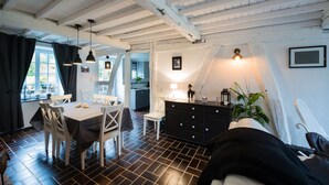 Un área de comedor con una mesa y sillas, una cocina al fondo y una escalera que sube a un nivel superior.