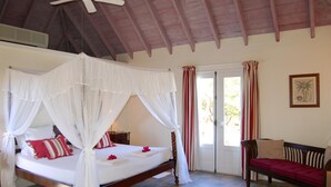 A bedroom with a four-poster bed, a wooden bench, a ceiling fan, and a door leading outside. - Armor (1/3 Rooms) Luxury villa (Pointe Milou - Montjean)
