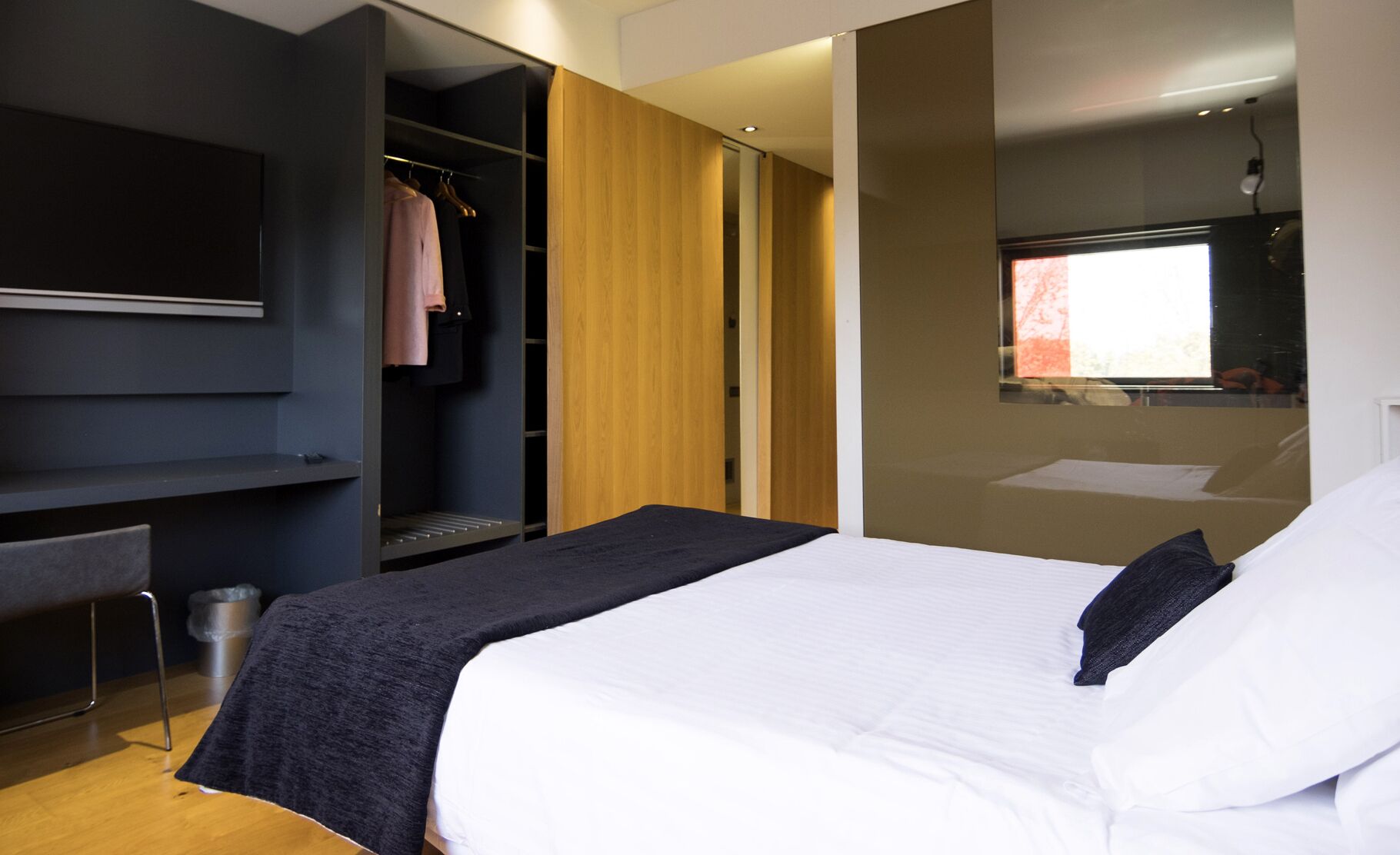 Quarto de hotel moderno com uma cama, um guarda-roupa e uma escrivaninha.