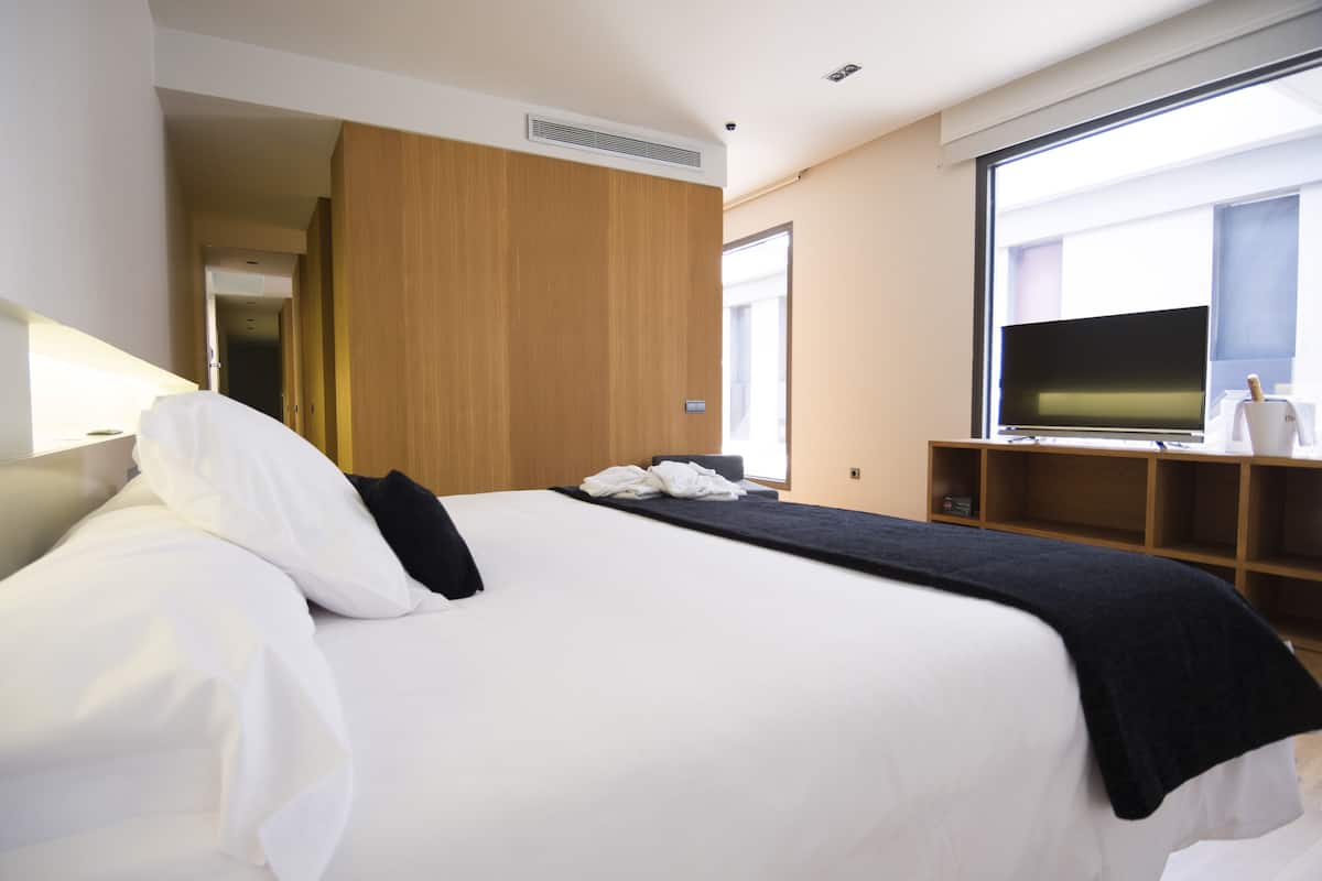 Een hotelkamer met een groot bed, een televisie, een houten garderobe en een raam met uitzicht.