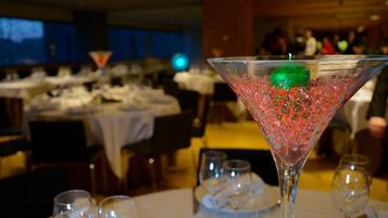 A martini glass with a green candle and red beads on a table in a restaurant setting.