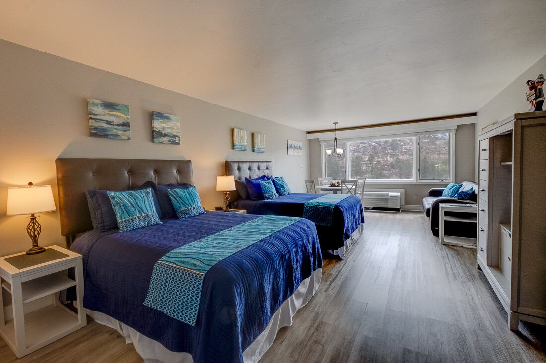 A bedroom with two beds, a nightstand, a desk, and a wardrobe.