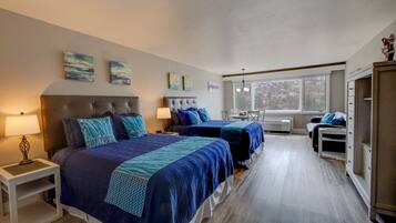 A bedroom with two beds, a nightstand, a desk, and a wardrobe.