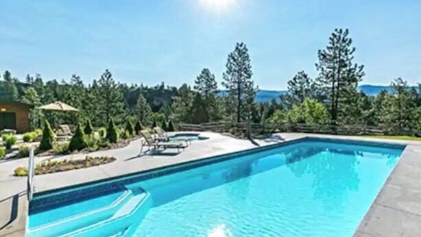 Una piscina rectangular con agua azul cristalina, rodeada por una terraza pavimentada.
