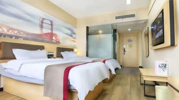 Habitación de hotel con cama, escritorio, silla, cubo de basura, un cuadro y una puerta.