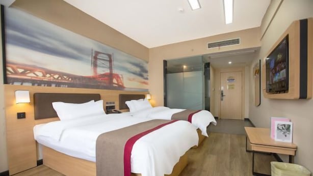 A hotel room with a large bed, a bedside table, a trash bin, and a painting on the wall. - Thank U Hotel (Lengshuijiang Red Double Happiness Building Material Market) (Lengshuijiang)