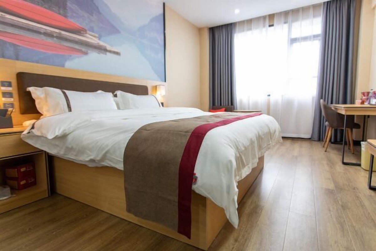A hotel room with a large bed, a desk, and a chair.