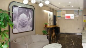 A modern lobby with a sofa, a round table, and a large abstract painting on the wall. - Thank U Hotel (Lengshuijiang Red Double Happiness Building Material Market) (Lengshuijiang)