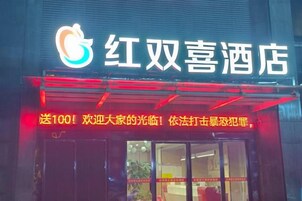 A hotel entrance with a neon sign and a red awning.