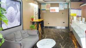 A hotel lobby with a sofa, a round table, a reception desk, and a wall with informational posters. - Thank U Hotel (Lengshuijiang Red Double Happiness Building Material Market) (Lengshuijiang)