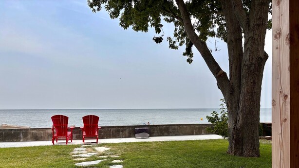 Une terrasse avec vue sur la mer, agrémentée de deux chaises rouges et d’un chemin en pierre.