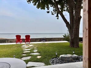 A patio with a view of the sea, featuring two red chairs and a stone pathway.