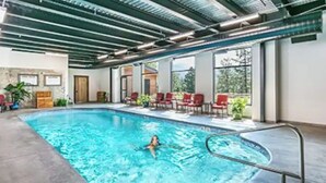 An indoor swimming pool with a person swimming, surrounded by red chairs and potted plants. - Basecamp for Your Mountain Adventure (Durango)