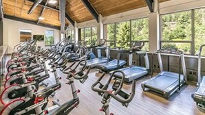 A gym with multiple exercise machines, large windows, and a wooden ceiling. - Basecamp for Your Mountain Adventure (Durango)