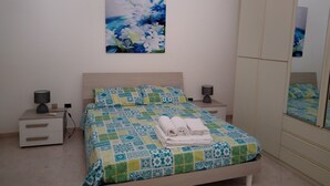 Une chambre à coucher comprenant un lit, deux tables de chevet, une commode, un miroir et un tableau accroché au mur.
