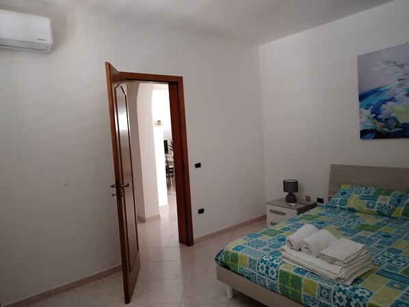 Un dormitorio con una cama, una mesita de noche, una lámpara y un cuadro en la pared.