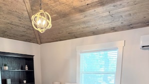 A bedroom with a bed, a nightstand, a bookshelf, a window, and a ceiling light fixture. - Coastal Cottage in Charming Old Mt Pleasant! (Mount Pleasant)