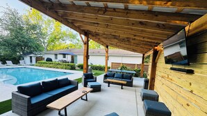 An outdoor patio area with a pool, wicker furniture, and a wooden pergola. - Coastal Cottage in Charming Old Mt Pleasant! (Mount Pleasant)