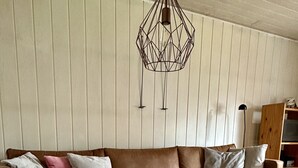 Un salon chaleureux avec un canapé en cuir marron, une table basse en bois et un tapis blanc à longues mèches.