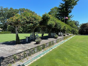 A well-maintained golf course with a stone pathway, wooden pergolas, and seating areas.