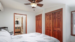 Une chambre à coucher avec un lit, une armoire en bois et un ventilateur de plafond.
