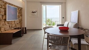A dining area with a round table, chairs, and a red bowl. There is a stone wall with a framed picture and a balcony with white chairs. - Apartment Oliva Verdello - Maina Country Resort - with pool, in Sicily (Naso)