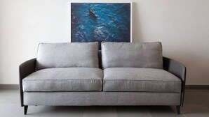 A grey sofa with black legs in a room with a tiled floor. - Apartment Oliva Verdello - Maina Country Resort - with pool, in Sicily (Naso)