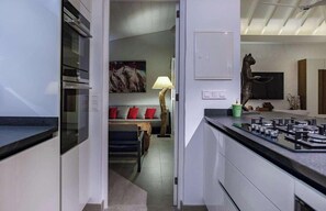Une cuisine moderne équipée d’une cuisinière à gaz, un coin repas avec un canapé et une lampe, et un tableau accroché au mur.