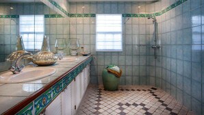 Ein Badezimmer mit gefliestem Boden, einem Waschbecken mit Spiegel und einer Duschkabine.