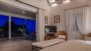 Ein Schlafzimmer mit einem großen Bett, einem Fernseher und einer Sitzecke mit Stühlen und einem Tisch.