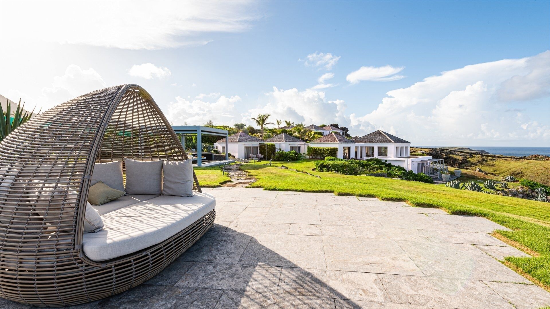 A coastal property with a large patio, a wicker lounge chair, and a view of the ocean.