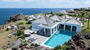 Een modern huis met zwembad, grote ramen en uitzicht op zee.